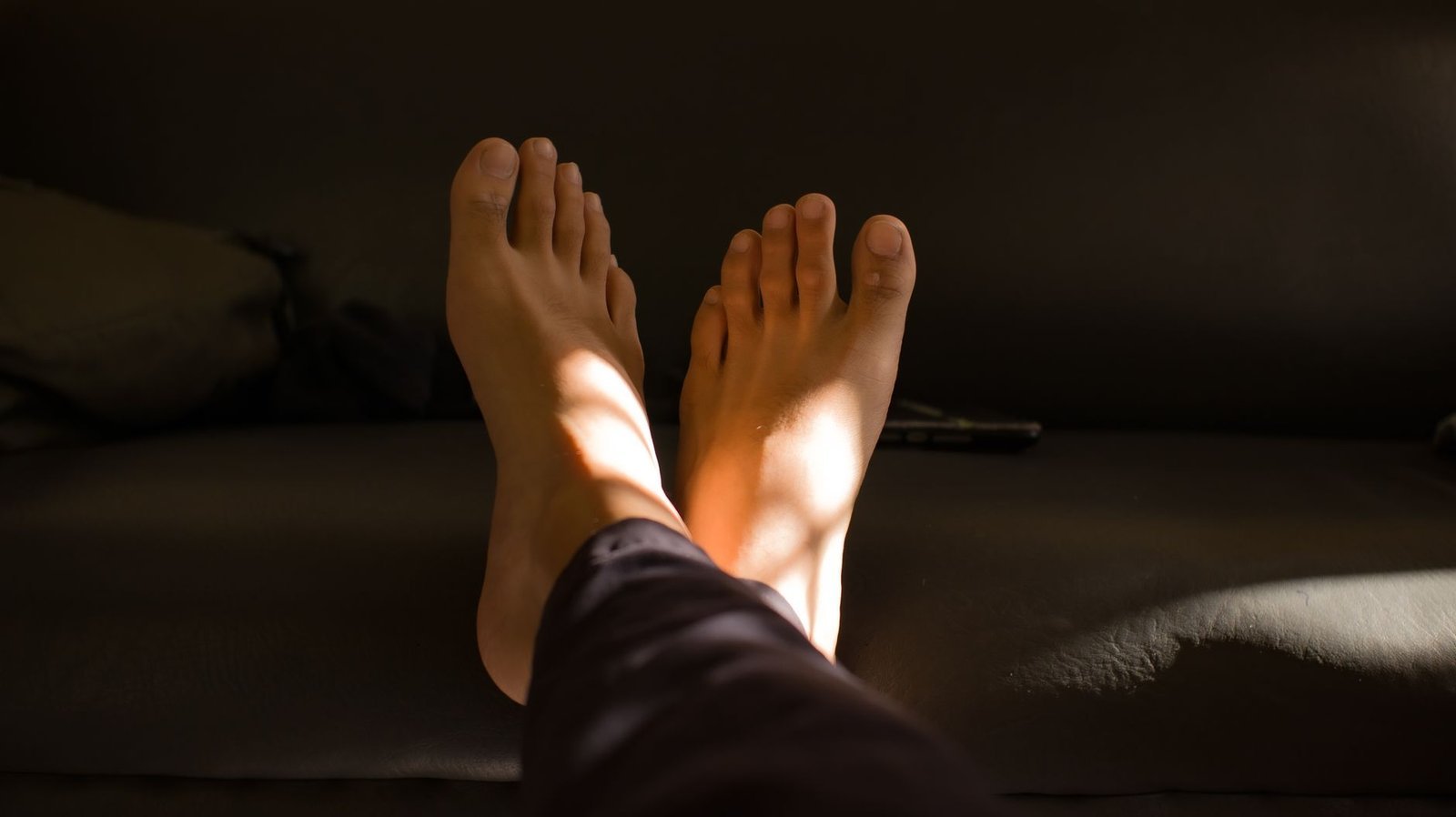 Piedi appoggiati sul divano, illuminati da un raggio di sole nel pomeriggio