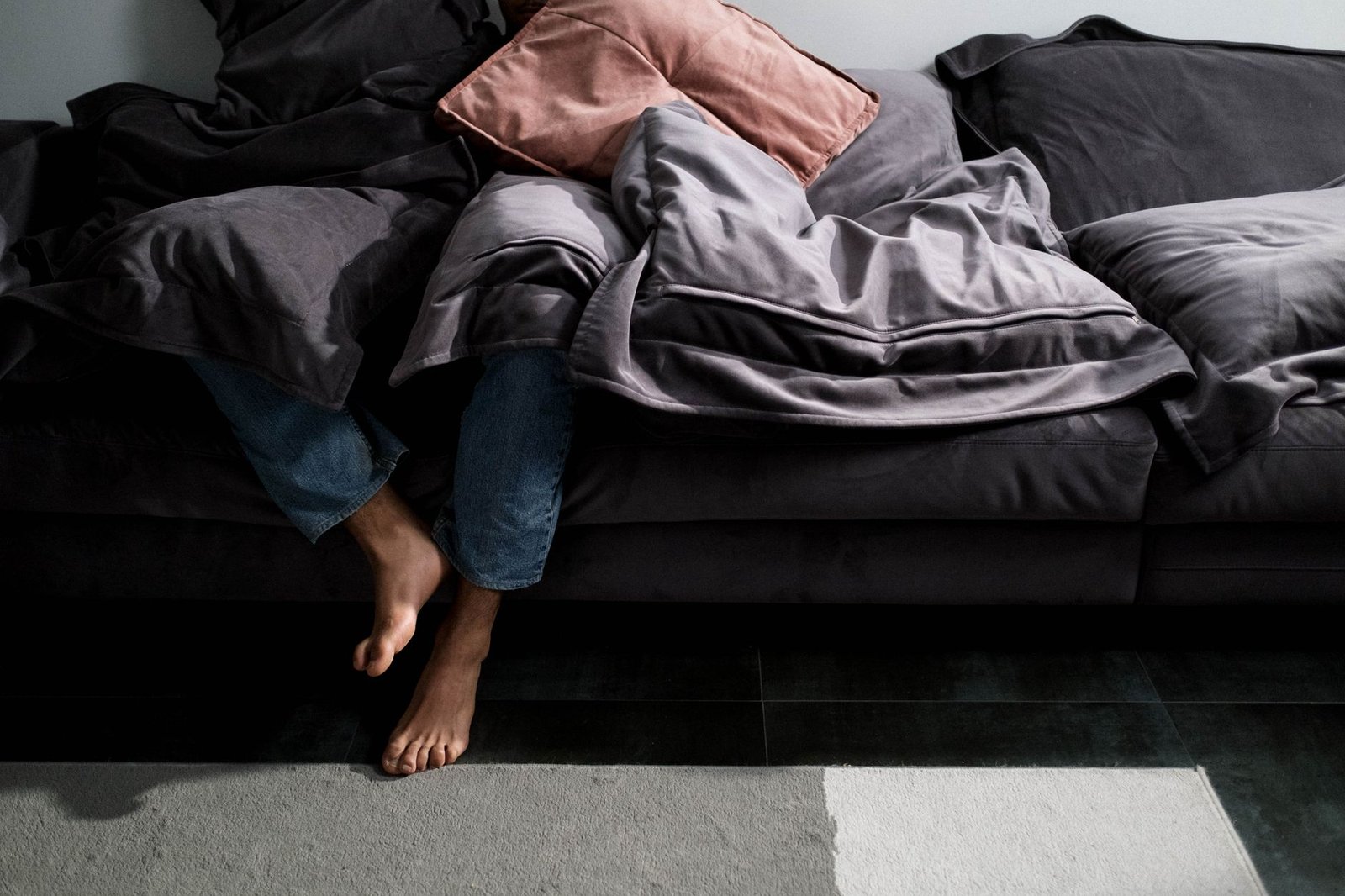 Piedi che spuntano da una coperta sul divano, fine di una giornata stanca