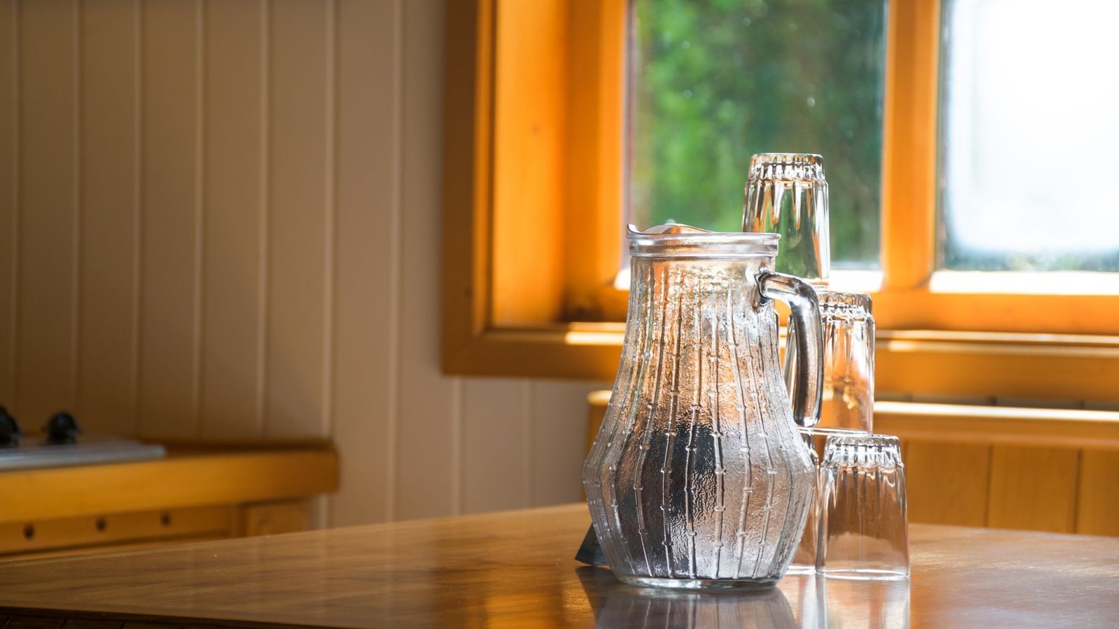 Caraffa d'acqua e bicchieri su un tavolo di cucina, nella luce della finestra