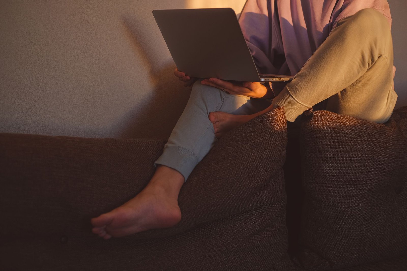Gambe ferme, al computer sul divano, la posizione tenuta per ore la sera