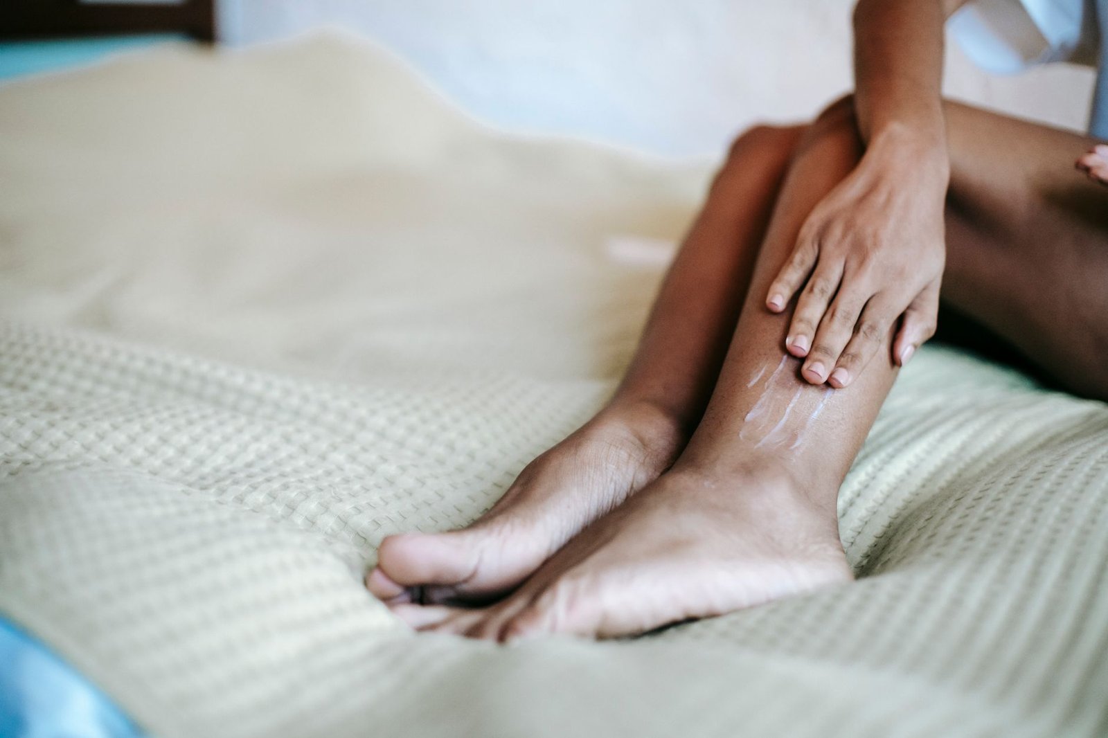 Una mano che tocca la caviglia, controllando la pelle tesa, seduta sul letto