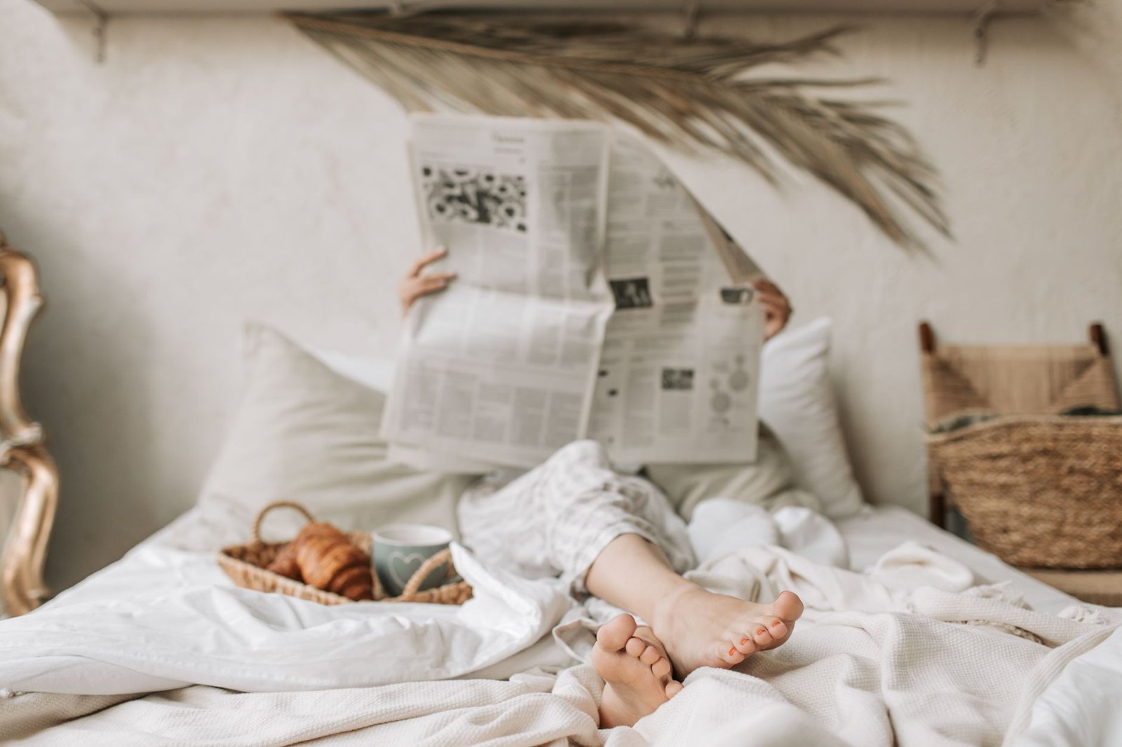 Piedi scalzi che spuntano dal letto disfatto, il viso coperto dal giornale, colazione lì accanto