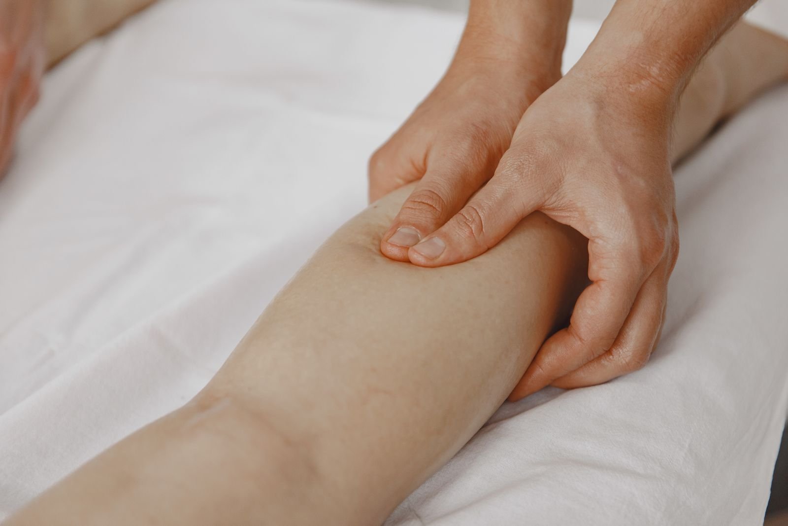Mani che premono sul polpaccio dal basso verso l'alto, il gesto della pressoterapia